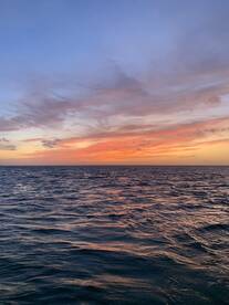 A breathtaking sunset over the ocean, showcasing vibrant colors reflecting on the water — a perfect moment for serene evening cruises.
