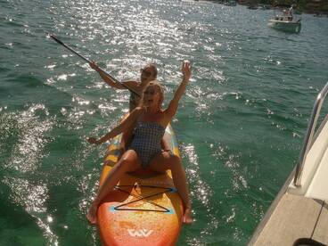 Two friends enjoy paddleboarding in sparkling waters, showcasing the fun and excitement of on-water activities during their boating adventure.
