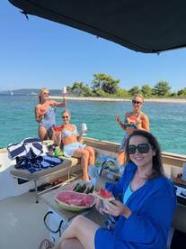 A lively group of friends enjoys a fun day on the water, sharing watermelon and drinks aboard a boat — perfect for summer celebrations and memorable outings.