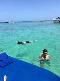 Two individuals enjoy a refreshing swim in crystal-clear waters, with one snorkeling nearby — a perfect snapshot of fun and adventure on the water.