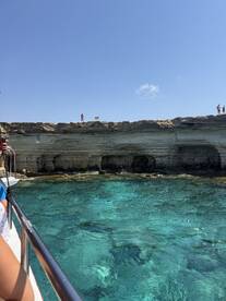 A stunning view of a rocky coastline with clear turquoise waters, showcasing guests enjoying a boat trip — perfect for exploring beautiful marine landscapes.