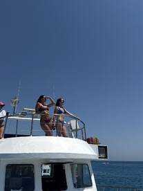 Two women enjoy the sun on the deck of a boat, taking in the beautiful ocean views — a perfect moment for summer adventures on the water.