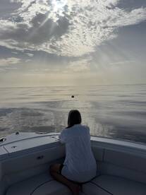 A serene moment as a woman gazes out over calm waters, reflecting the beauty of the sky — perfect for peaceful sunset cruises.