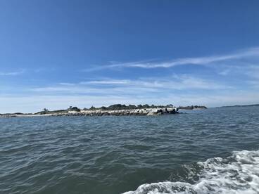 A picturesque view of a rocky coastline under a clear blue sky, showcasing the beauty of the surrounding waters and natural landscape.