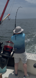 A fisherman battles a catch on the open water, showcasing the excitement of deep-sea fishing adventures.