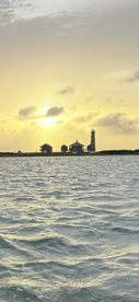 A stunning sunset view featuring a lighthouse and coastal buildings, creating a picturesque backdrop over the water — perfect for capturing the beauty of maritime landscapes.