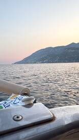 A serene view from a boat at sunset, showcasing the calm waters and distant mountains — perfect for peaceful evening cruises.