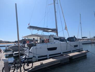 A catamaran named 'Isla 40' docked at the marina with people onboard, showcasing a perfect setting for sailing adventures.