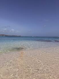 A serene view of a clear turquoise beach with gentle waves, perfect for relaxation and enjoying the beauty of nature.