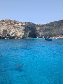 A stunning view of a coastal cave with crystal-clear blue waters, perfect for exploring and enjoying the natural beauty of the surroundings.