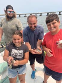 A joyful family displays their catch while fishing on a boat, showcasing a fun day on the water filled with laughter and memorable moments.