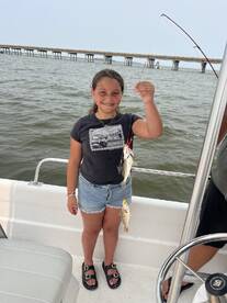 A young girl proudly displays her catch while fishing from a boat, capturing the joy of a family fishing trip on the water.
