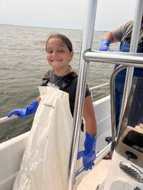 A young girl smiles while aboard a boat, showcasing a fun day on the water. This image captures the joy of marine activities and the excitement of being out at sea.