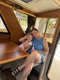 A mother and her daughter enjoy a cozy moment inside the cabin of a boat, showcasing the inviting interior space perfect for family outings.