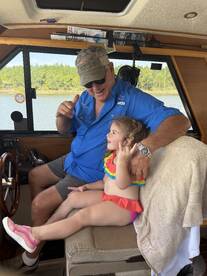 A joyful moment inside the boat's cabin, featuring a man and a young girl sharing a fun interaction at the helm — perfect for family boating adventures.