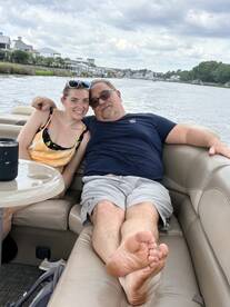 A cheerful couple relaxes on the seating of a pontoon boat, enjoying their time on the water — perfect for family outings or leisurely cruises.