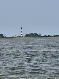 A distant view of a lighthouse on the horizon, partially obscured by water reflections, creating an unclear image.