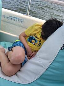 A young child peacefully naps on a comfortable seat aboard a boat, showcasing a relaxing moment on the water.