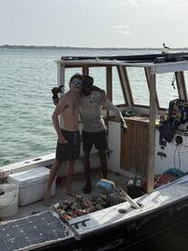 Two friends celebrate their fishing catch aboard a boat, showcasing camaraderie and the joy of a successful day on the water.