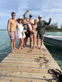 A joyful family poses for a group photo on a dock, showcasing their fun day at the beach — perfect for capturing memorable moments during a boating adventure.