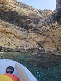 A scenic view of a boat near a rocky coastline, showcasing clear waters and natural rock formations — perfect for exploring hidden coves.