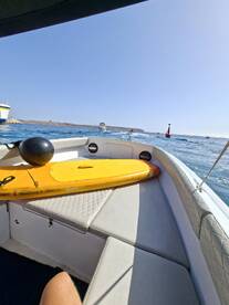 A view of the interior of a boat featuring a paddleboard and comfortable seating, perfect for a day of relaxation and water activities.