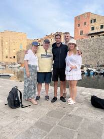 A cheerful group poses together at a picturesque harbor, capturing a memorable moment during their boating adventure.