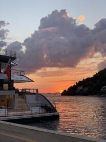 A stunning sunset view featuring a luxurious yacht docked, with vibrant clouds reflecting the evening light — perfect for capturing serene moments on the water.