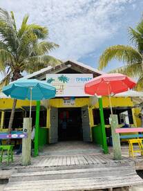 A vibrant beach bar named 'Footprints' featuring colorful umbrellas and palm trees, perfect for enjoying refreshments by the shore.