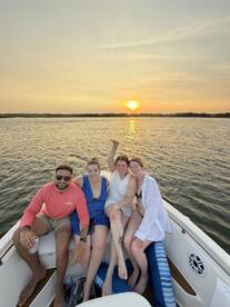 A joyful group of friends enjoys a sunset cruise on a boat, capturing the perfect moment of celebration and camaraderie on the water.