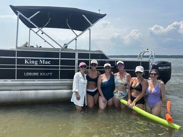 A fun group of friends enjoys a sunny day in the water next to their pontoon boat, 'King Mac,' perfect for summer gatherings and celebrations.