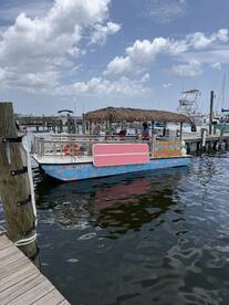 A colorful tiki boat docked at the marina, surrounded by clear waters and a picturesque sky — perfect for fun outings and group adventures.