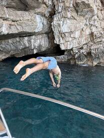 A child jumps into the crystal-clear waters near a rocky coast, showcasing a fun and adventurous moment perfect for family outings and snorkeling adventures.