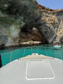 A stunning view of a boat approaching a natural cave, surrounded by crystal-clear turquoise waters — perfect for exploring coastal wonders.