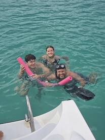 A group of friends enjoys snorkeling in clear aquamarine waters, showcasing a fun and adventurous day on the water.