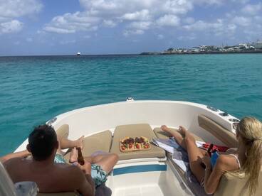 A couple enjoys a relaxing day on the water, sipping drinks and snacking on a platter while taking in the beautiful turquoise sea — the perfect setting for a romantic getaway.