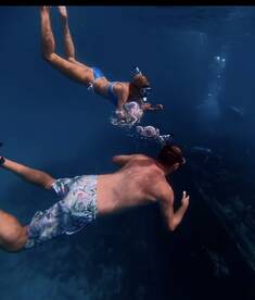 A couple enjoys snorkeling underwater, exploring vibrant marine life and bubbles in a stunning aquatic environment — perfect for adventure seekers.
