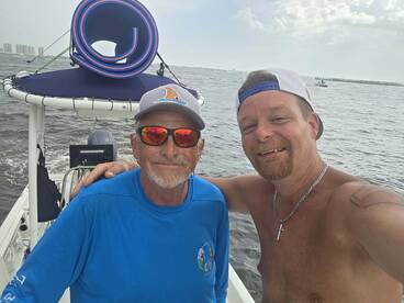 Two men pose for a selfie on a boat, enjoying a day on the water. The camaraderie and scenic backdrop highlight the fun of boating adventures.