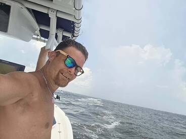 A man enjoys a sunny day on the water, capturing a selfie while boating — a perfect moment for ocean adventures.