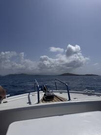 A clear view of the bow of a boat cutting through the water, showcasing the serene ocean and distant islands — perfect for adventure seekers and boating enthusiasts.
