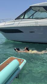 A woman swims in clear waters near a sleek Sea Ray boat, showcasing a perfect day of fun and relaxation on the water.