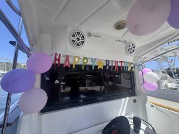 A festive interior of a boat adorned with a 'Happy Birthday' banner and colorful balloons, perfect for celebrating special occasions on the water.
