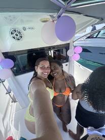 Two friends pose for a selfie on a boat, celebrating with decorations and enjoying their time together — perfect for memorable boat parties.