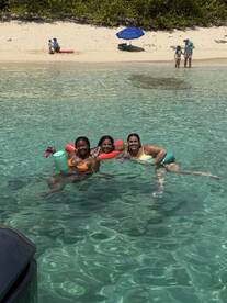 A joyful group of friends enjoys a sunny day swimming in crystal-clear waters, creating unforgettable memories at the beach.
