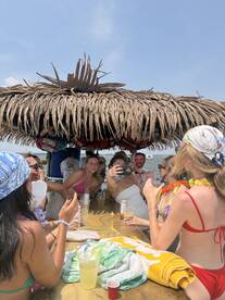 A lively group enjoys drinks and captures memories at a beachside bar, perfect for summer celebrations and social gatherings.