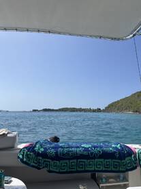 A cozy interior view of a boat featuring a colorful towel draped over the seating area, perfect for relaxing while enjoying the scenic waterfront.