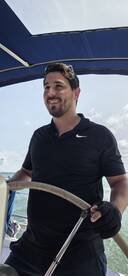 A man confidently steers the boat from the helm, showcasing the interior space and the joy of navigating the open waters.
