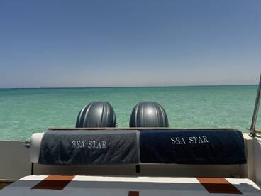 A view of the interior seating area on a boat named 'Sea Star', showcasing the serene turquoise waters in the background, perfect for relaxing on a sunny day.