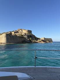 A stunning view of a historic fortress overlooking turquoise waters, captured from the deck of a boat — a perfect backdrop for exploring coastal landmarks.