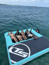 A lively group enjoys a fun day on a floating mat in the water, showcasing the perfect atmosphere for summer parties and aquatic adventures.